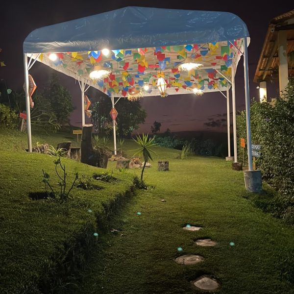 Tenda decorada e iluminada em jardim durante evento noturno