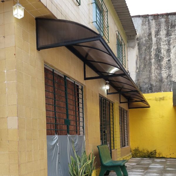 Toldo curvo escuro instalado sobre portas e janelas