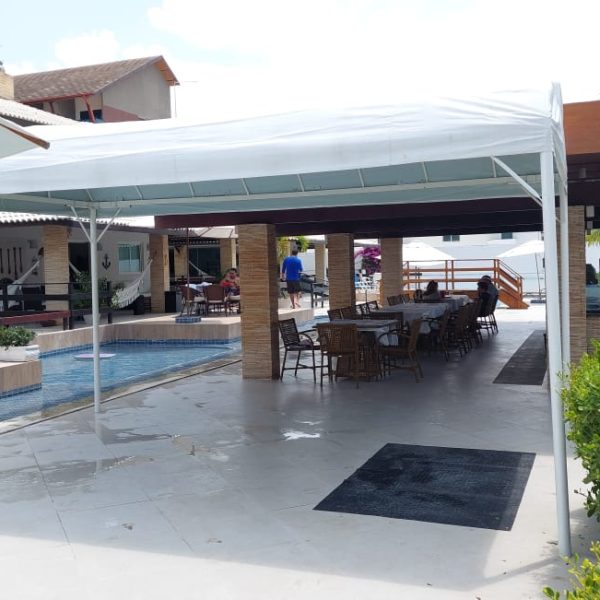 Tenda branca ampla cobrindo área de convivência
